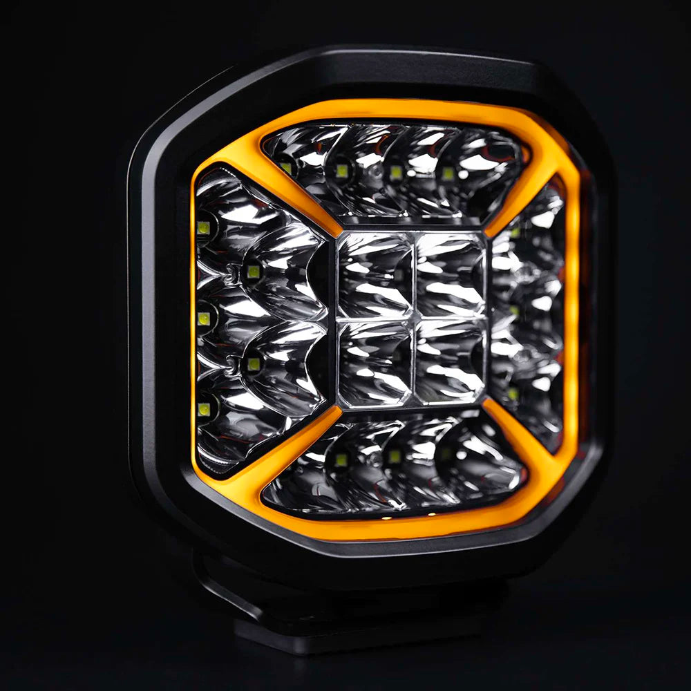 Strands Siberia X 7" lisävalo upealla oranssilla kehäparkilla joka kiertää valaisimen reunat ja kulmat tulevat keskikohtaa kohden muduostaen X kuvion. Valo on 8 kulmainen suorakaide. Mustalla taustalla.