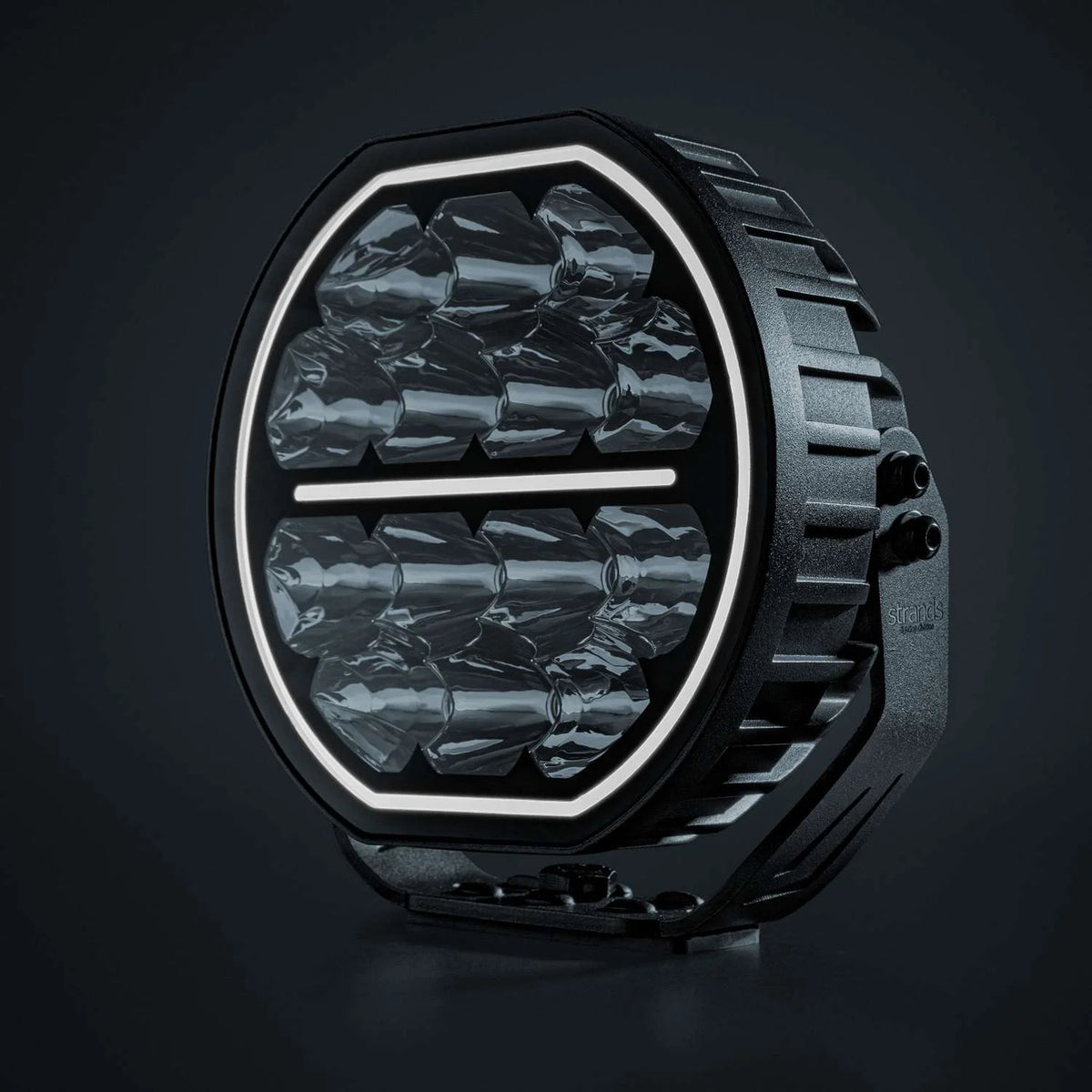 Strands Big Energy 7" pyöreä lisävalo missä tasainen ylä- ja alaosa. Valkoinen parkkivalo kiertää valon sisäreunaa, sekä keskellä valkoinen parkkiviiva. Valo kuvattu mustaa taustaa vasten.