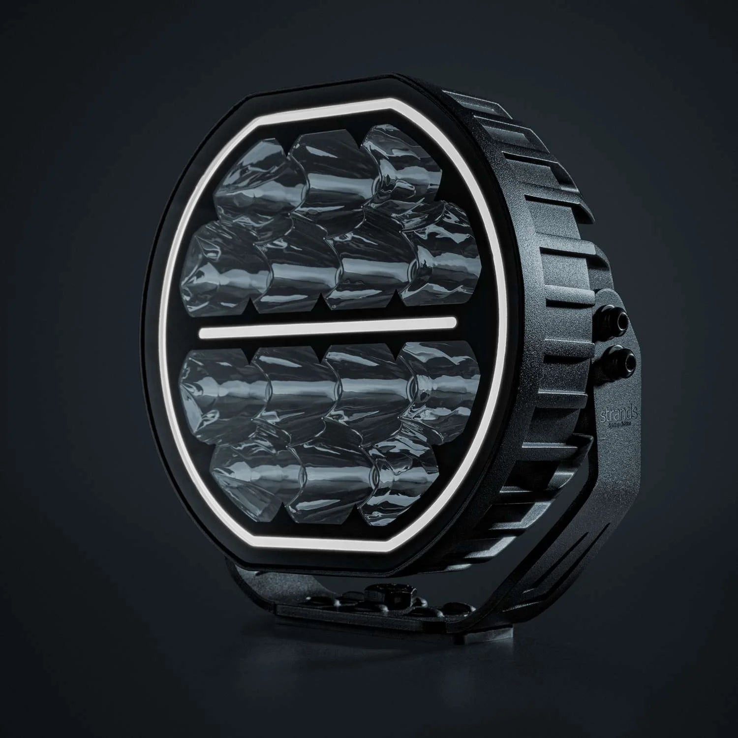Strands Big Energy 7" pyöreä lisävalo missä tasainen ylä- ja alaosa. Valkoinen parkkivalo kiertää valon sisäreunaa, sekä keskellä valkoinen parkkiviiva. Valo kuvattu mustaa taustaa vasten.