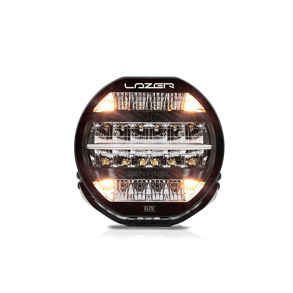 Musta 9-tuumainen Lazer Sentinel 9 Elite -lisävalo pyöreällä muotoilulla, oransseilla parkkivaloilla ja monirivisillä heijastimilla. Valo on kuvattu etuviistosta valkoista taustaa vasten.