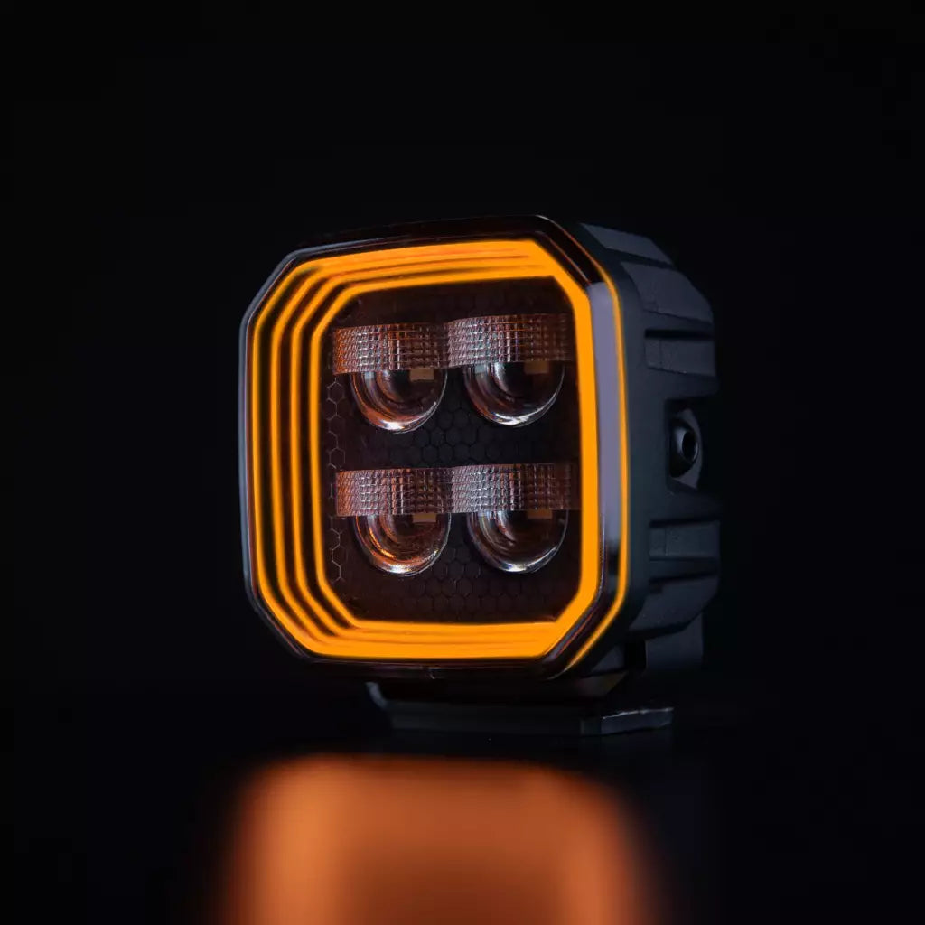 Strands For9t häikäisemätön led-työvalo mustaa taustaa vasten ja oranssi upea parkki kiertää valon sisäpintaa neljässä eri tasossa. Keskellä neljä eri heijastinelementtiä. Valo on muodoltaan neliö ja leikatut kulmat.