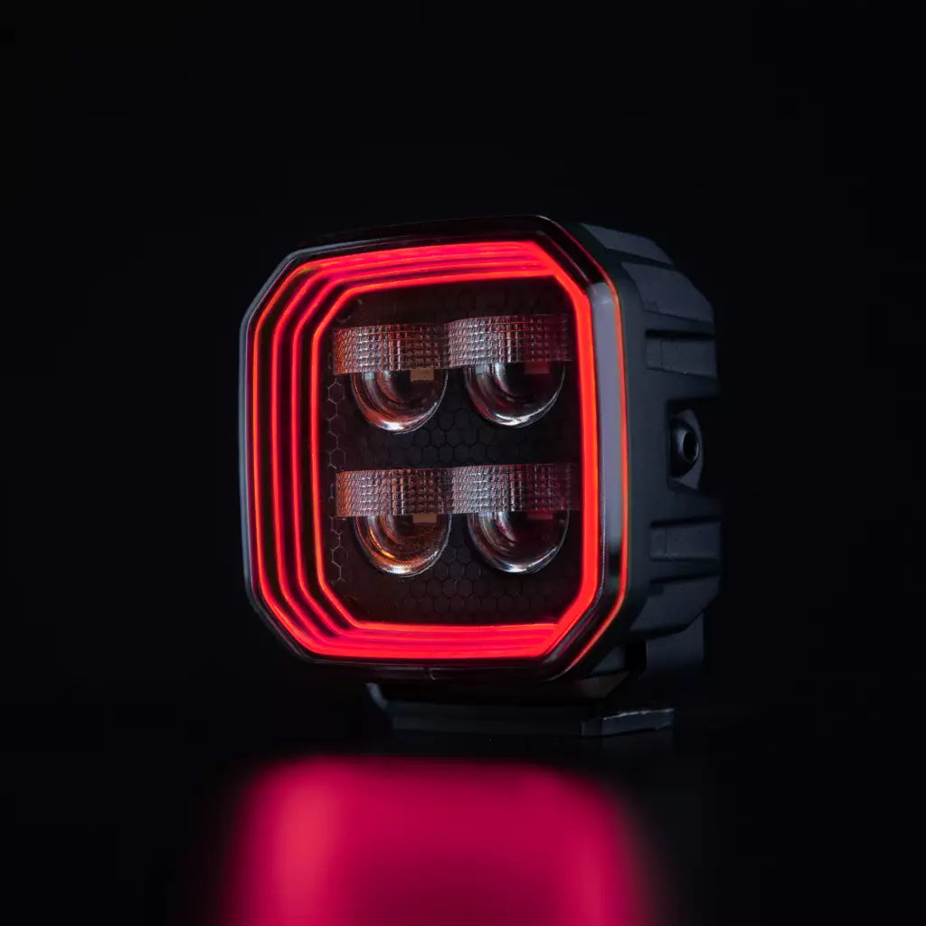 Strands For9t häikäisemätön led-työvalo mustaa taustaa vasten ja upea punainen parkki kiertää valon sisäpintaa neljässä eri tasossa. Keskellä neljä eri heijastinelementtiä. Valo on muodoltaan neliö ja leikatut kulmat.