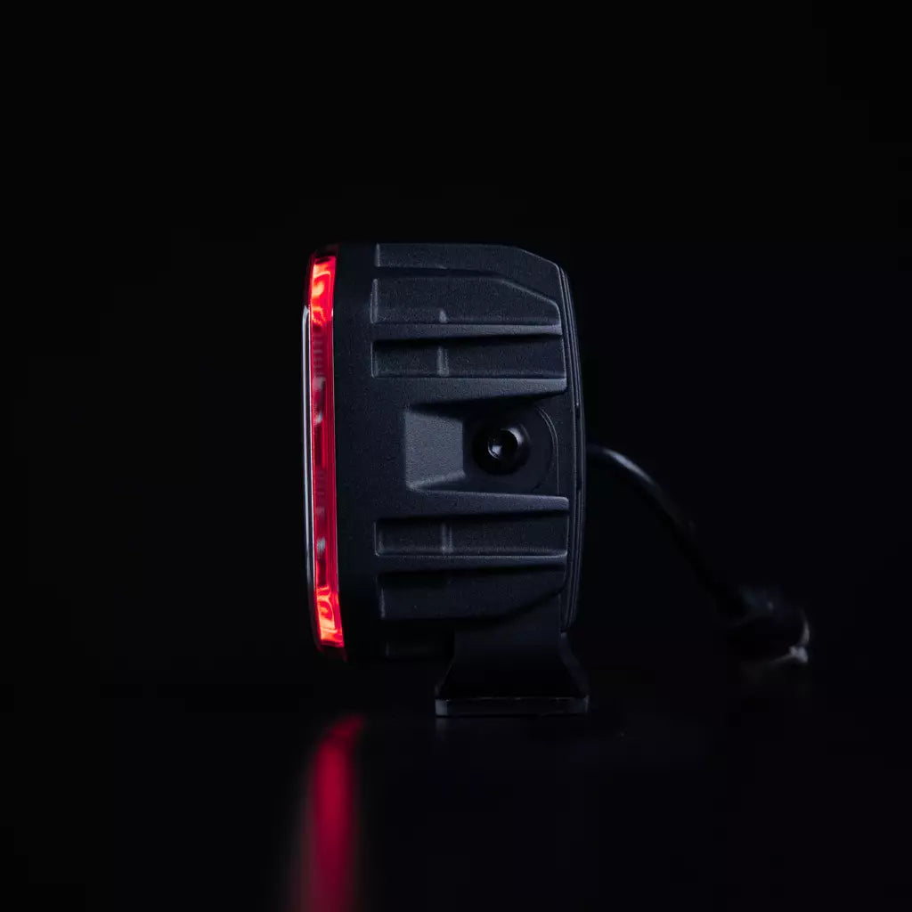 Strands For9t häikäisemätön led-työvalo mustaa taustaa vasten suoraa sivusta kuvattuna ja upea oranssi parkki kiertää valon etureunaa neljässä eri tasossa.