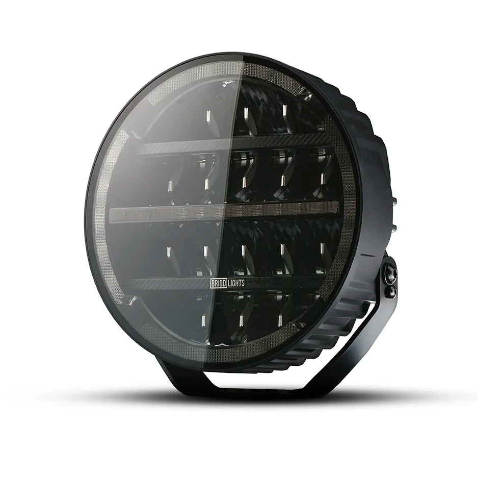 BriodLights Olympus 9-tuumainen pyöreänmuotoinen lisävalo mustassa värissä. Valossa heijastimet neljässä rivissä ja reunoja mukaillen sijoitetut parkkivalot. Kuvattu etuviistosta ja valkoista taustaa vasten.