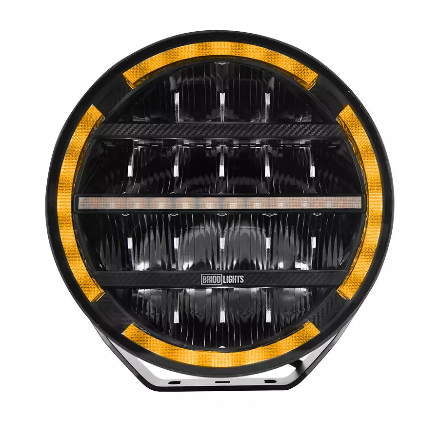 BriodLights Olympus 9-tuumainen pyöreänmuotoinen lisävalo mustassa värissä. Valossa heijastimet neljässä rivissä ja reunoja mukailevat parkkivalot oranssilla ledillä. Kuvattu edestä ja valkoista taustaa vasten.