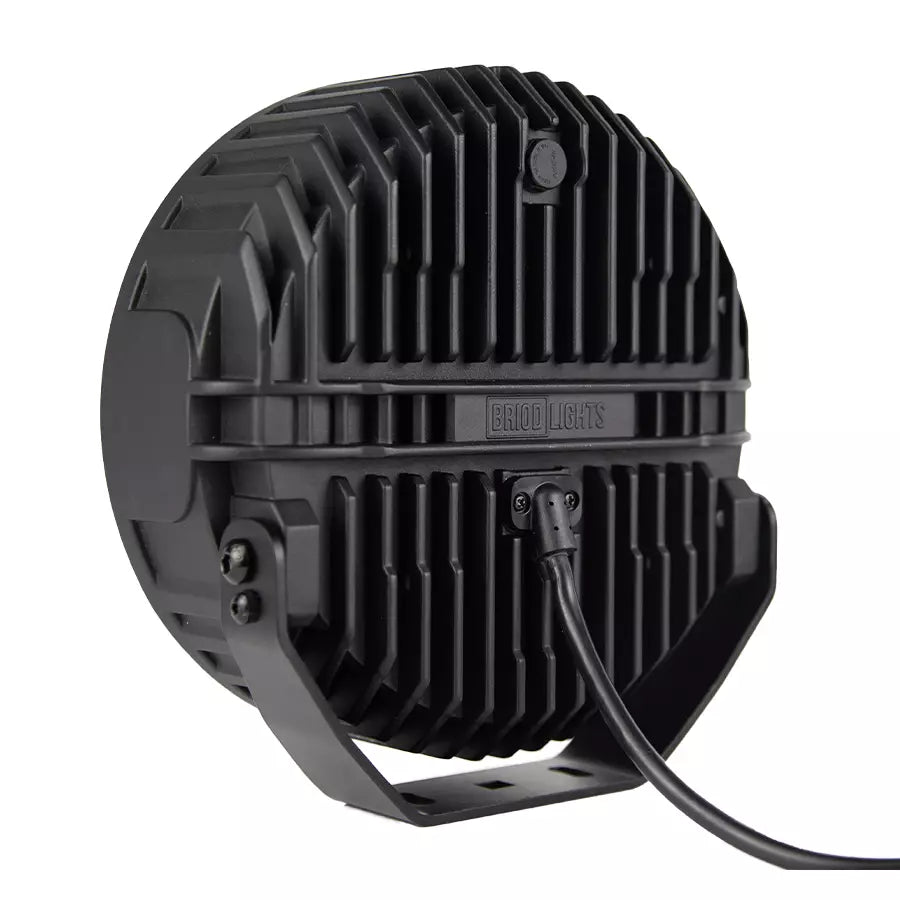 BriodLights Olympus 9-tuumainen pyöreänmuotoinen lisävalo takaviistosta kuvattuna jalallaan seisten. Kuvattu valkoista taustaa vasten.