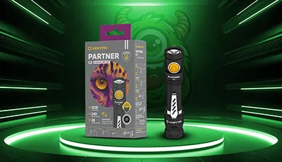 Armytek Partner led taskulamppu vihreällä Valomonsteri taustalla. tyylikkäässä studioympäristössä, ossa valaistu vihreä koroke.